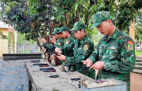 Trung uý Lê Thanh Hiếu (thứ nhất từ phải sang) đang lau chùi, bảo quản trang bị vũ khí.